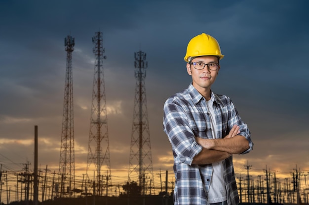 Asian engineer man entrepreneur constrcution industry male engineer crossed arms working at electric polepower plant manufacturing Civil engineering construction wear yellow hardhat safety helmet