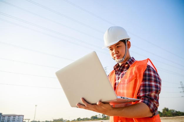 Asian engineer manager using computer laptop at construction\
site project on workplace