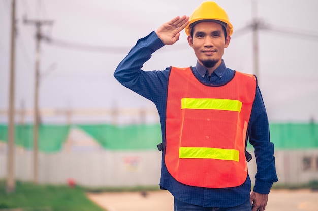 Ingegnere asiatico in piedi all'aperto sul sito di costruzione che pubblica fiducioso ingegnere nella costruzione di un lavoro felice con successo nella pianificazione dell'obiettivo