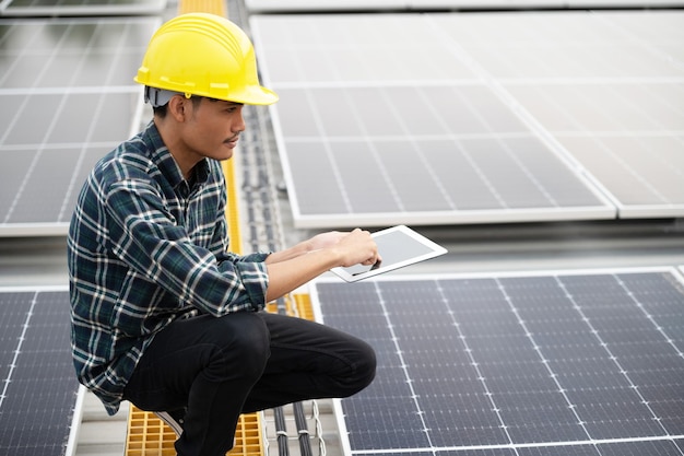 Asian engineer using tablet checking in solar power system for industrial ecology control top roof factory