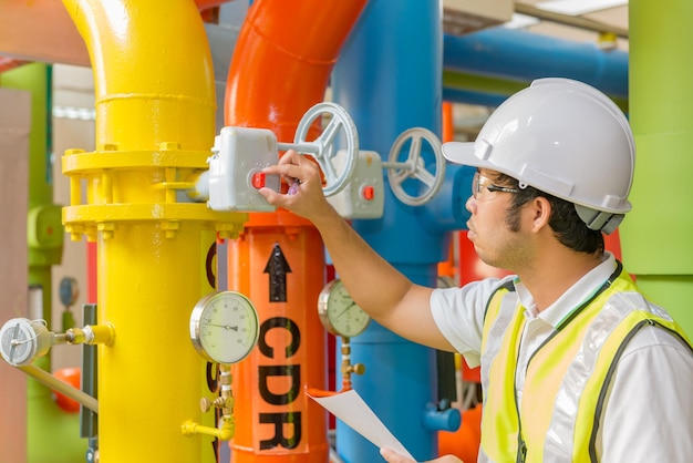 Asian engineer wearing glasses working in the boiler roommaintenance checking technical data of heating system equipmentthailand people