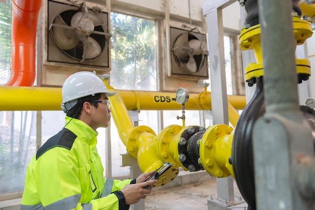 Asian engineer wearing glasses working in the boiler roommaintenance checking technical data of heating system equipmentThailand people