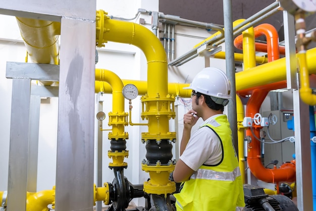 Asian engineer wearing glasses working in the boiler roommaintenance checking technical data of heating system equipmentThailand people