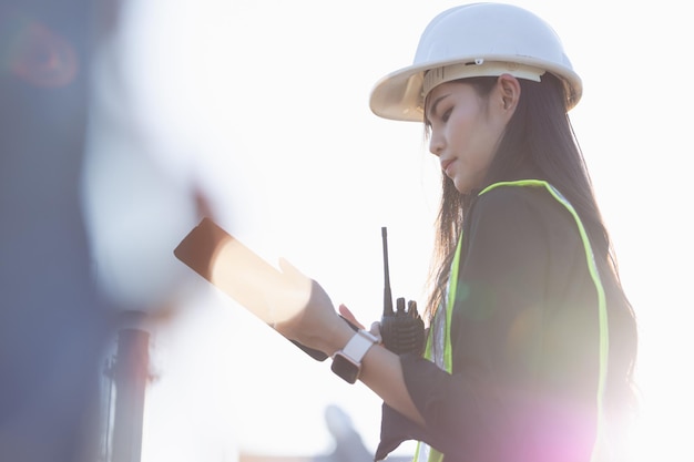Фото Азиатская женщина-инженер или архитектор смотрит вперед с белым защитным шлемом на строительной площадке