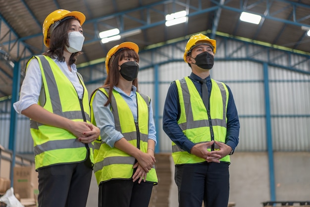 Asian engineers wearing mask protect and helmet safety meeting with teamwork at warehouse factory