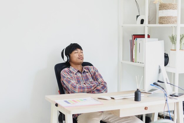 asian entrepreneur resting while listen to music with headphones while working