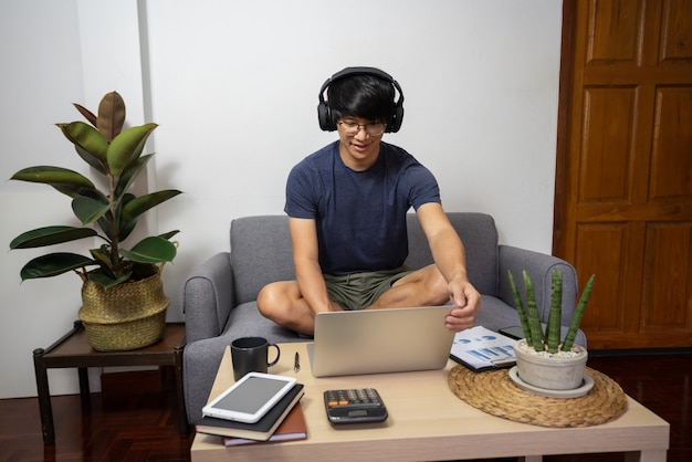 Asian entrepreneur working at home on some project with his laptop at home