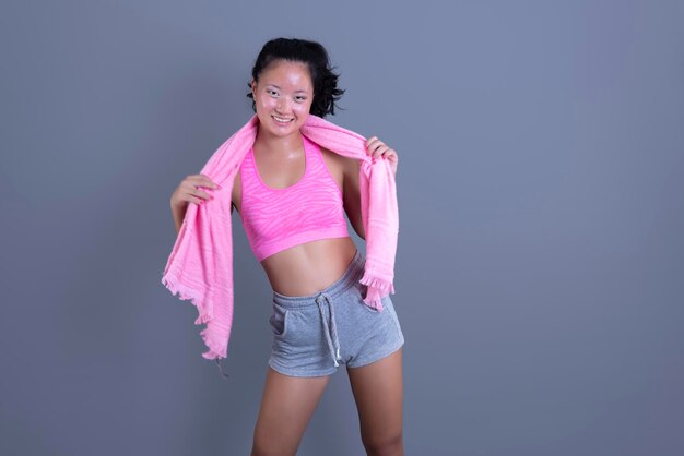 Asian ethnic woman in sportswear with towel around her neck isolated from the background