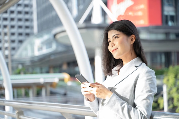 Asian executive working with a mobile phone in the street with office buildings in the background