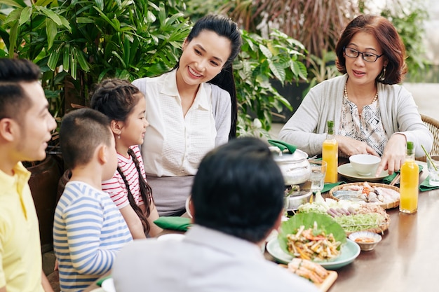 伝統的な料理を食べ、屋外の夕食のテーブルで話すアジアの家族