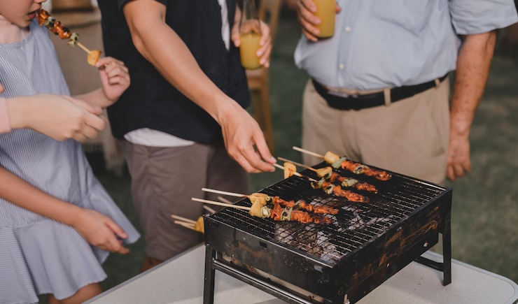 Photo 自宅でバーベキューパーティーをしているアジアの家族。裏庭で夕食にグリルバーベキューを調理します。夏休みのライフスタイル。