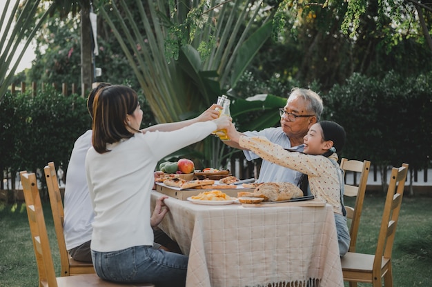 Asian family having pizza in garden at home. Parent with kid and grandfather lifestyle in backyard.