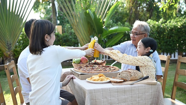 Asian family having pizza in garden at home. Parent with kid and grandfather lifestyle in backyard.