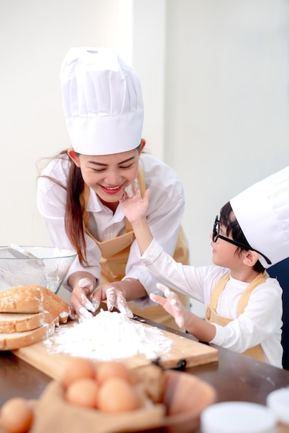 Asian family in the kitchen. Mom teaching son for cook healthy food in summer holiday.