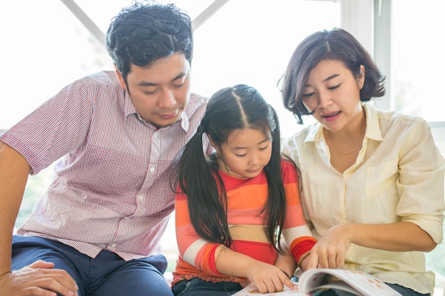 Asian family reading book with their children.