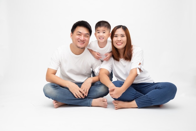 Asian family smiling and sitting together on floor isolated white wall. Young thai family concept