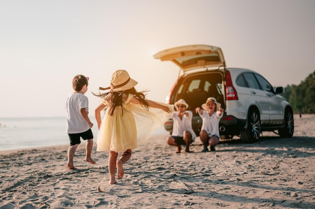 Vacanza in famiglia asiatica famiglia felice che corre sulla spiaggia al tramontoxai bambini corrono dai genitori dietro le autovacanza e concetto di famiglia di viaggio vacanze estive