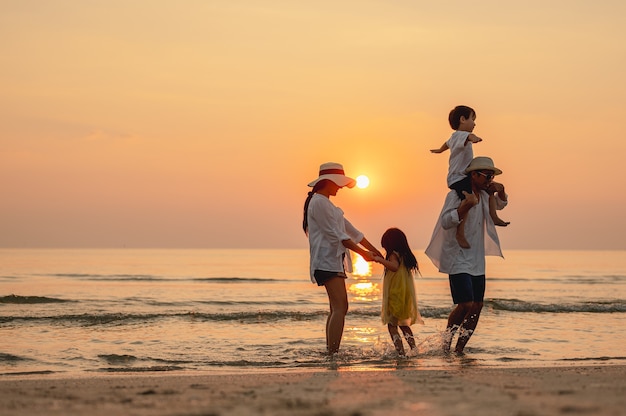 アジアの家族の休暇の休日空を飛んで子供を抱いて幸せな家族の両親