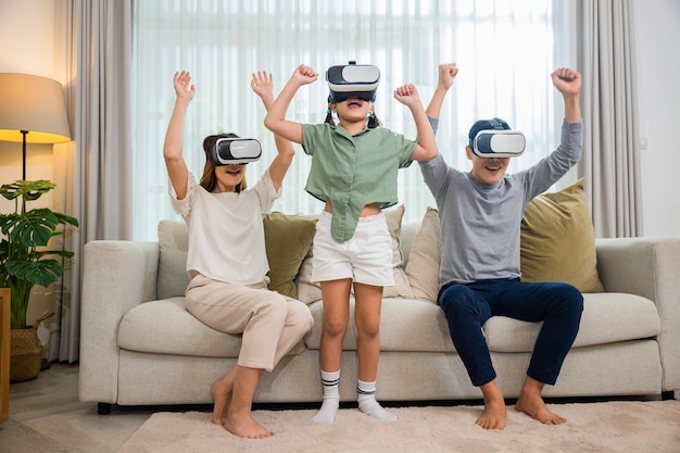 アジアの家族は、リビングルームのソファに座ってvrメガネのヘッドセットを着用し、ゲームエンターテイメントの革新技術、幸せな家族には、映画を見たりビデオゲームをしたりする母父と娘がいます