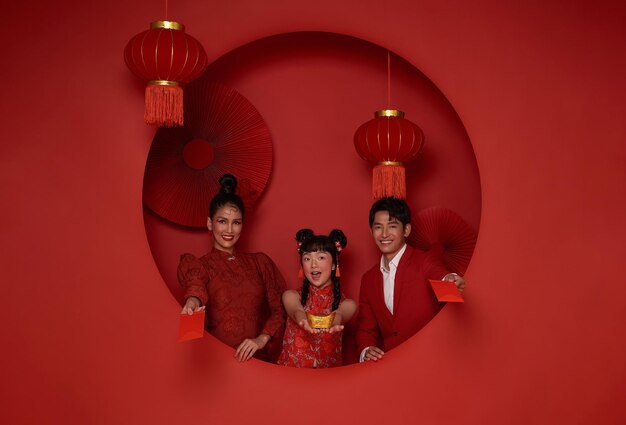 Asian family wearing traditional cheongsam qipao dress holding red envelope give Chinese new year