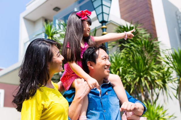 Азиатская семья с ребенком, стоя перед домом