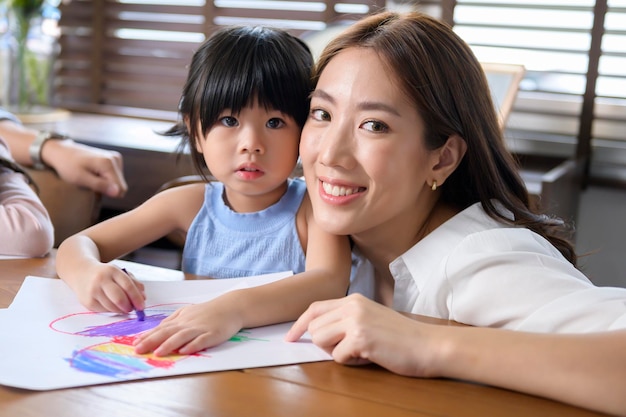 아이들이 있는 아시아 가족 집에서 놀고 있는 탁자에 그림 그리기 교육 게임