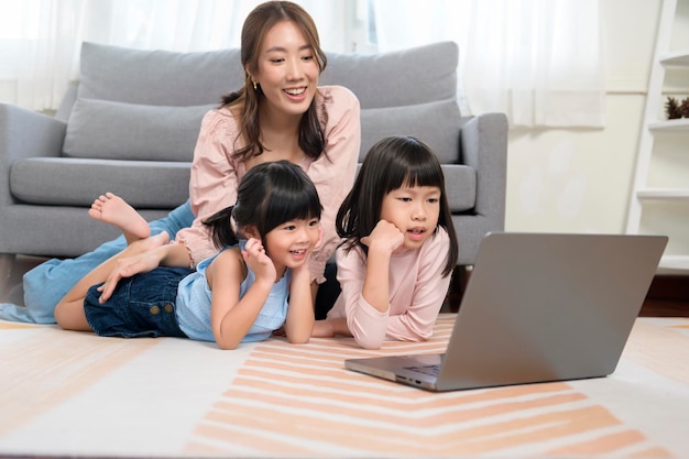 집에서 노트북 컴퓨터를 사용하는 아이들이 있는 아시아 가족