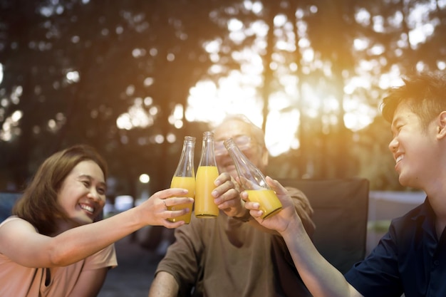 シニアの飲酒と一緒にバーベキューをしているアジアの家族。夏休みのキャンプ中に夕食にグリルバーベキューを調理します。