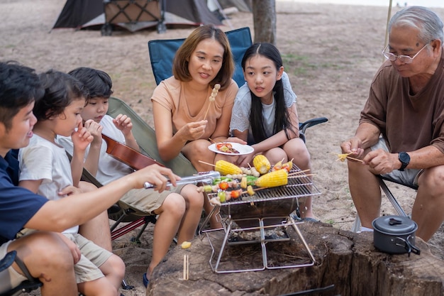 수석 음주와 함께 바베큐를 하는 아시아 가족. 여름 doliday에 캠핑하는 동안 저녁 식사를 위해 구운 바베큐 요리.