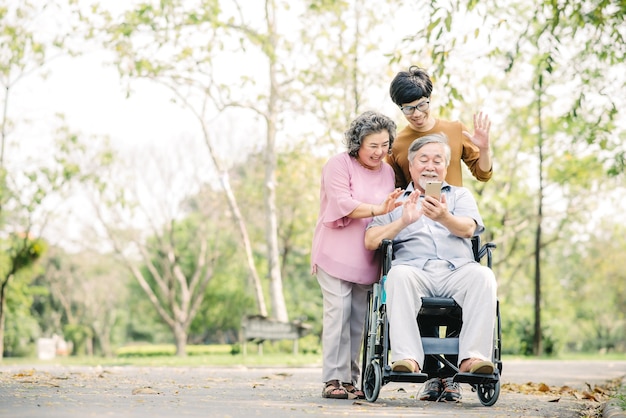 Asian family with young man and senior woman and man in wheelchair having fun