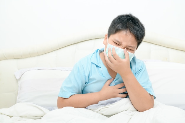 Asian fat boy wear surgical mask is
coughing and chest pain on bed,