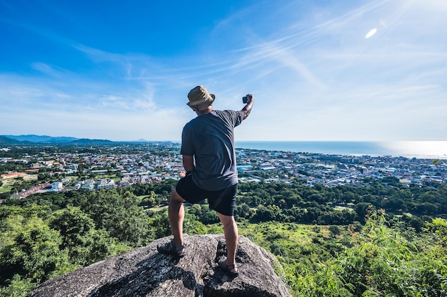 アジア人の太った男が岩の上に立って、カオヒンレックファイビューポイントで写真を撮りますカオヒンレックファイは町全体の壮大な景色を見る場所です地元の人々にはカオレーダーとしても知られています