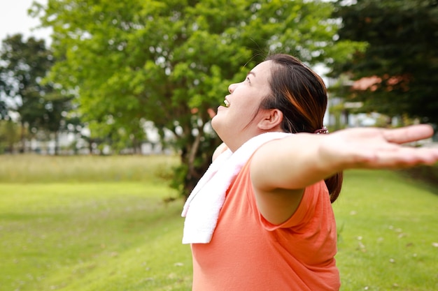 Foto donna grassa asiatica che sorride felice allungando le braccia esercizio all'aperto per perdere peso rendi il tuo corpo sano concetto di sport sanitari