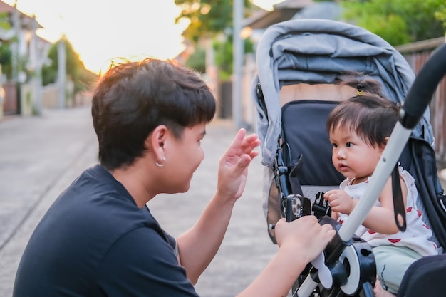 写真 アジアの父と娘または息子のかわいい女の子が幸せな気持ちでキスをし、ベビーカーで楽しむ