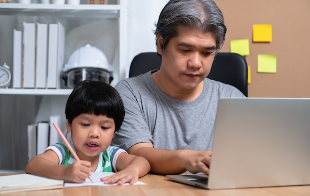 Asian father is work at the home with a daughter and studying online learning from school together