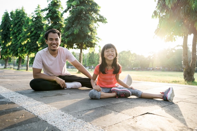 Asian father and little daughter do exercises in outdoor