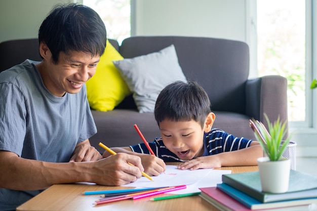 アジアの父と息子は家で絵を描くことを楽しんでいます。家族の活動と家庭での勉強の概念