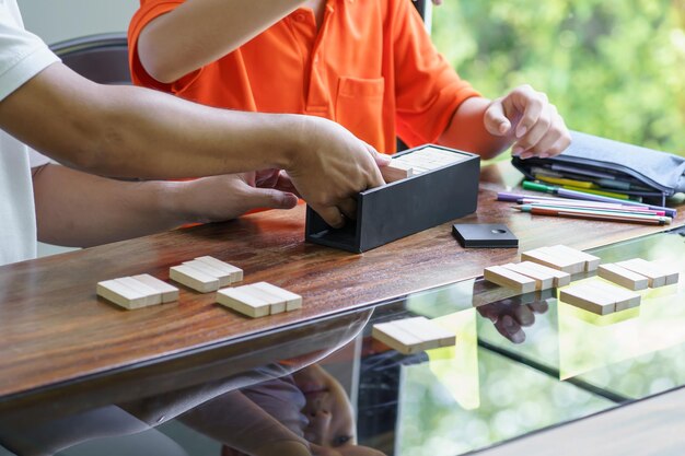 Asian father and son playing wood blocks game Carefree kid playing wood blocks game building constructor from blocks with father at home