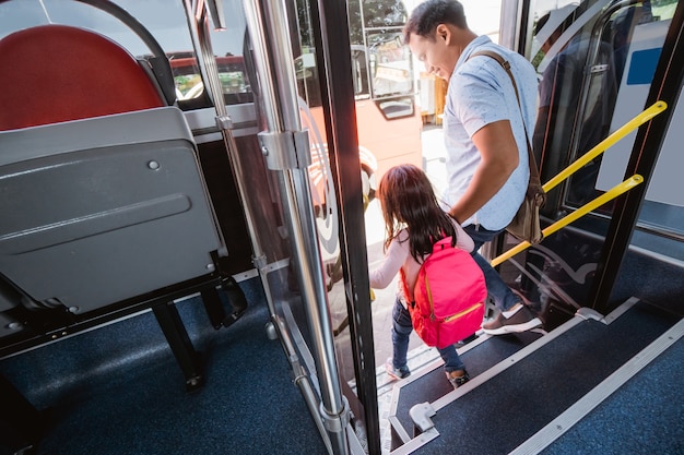 Asian father taking his daughter to school by riding bus public
transport