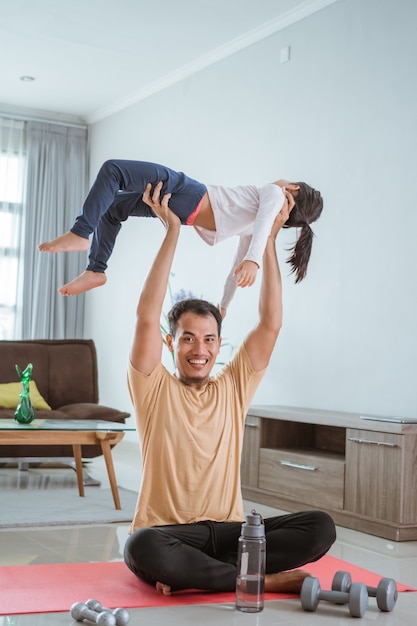 Asian father use his child as weight for lifting exercise at home