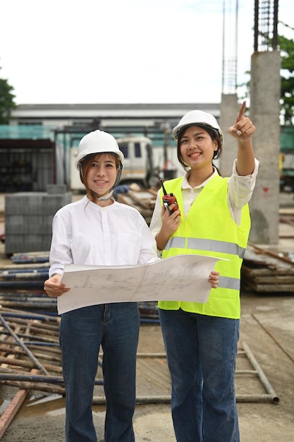 Asian female architect and supervisor discussing on plan while visiting a new building