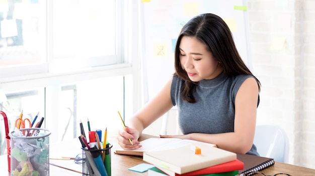 Asian female college student reading book at the table 