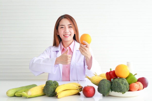 Medico o nutrizionista asiatico consultare il paziente sulla dieta c'erano vari tipi di frutta e verdura sdraiati sul tavolo bianco. concetti di assistenza sanitaria, alimentazione sana, perdita di peso