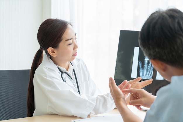 Photo asian female doctor and patient discussing something while sitting at the table