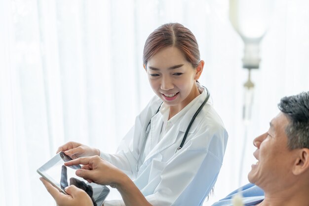 Photo asian female doctor sitting on hospital bed and discussing with senior patient