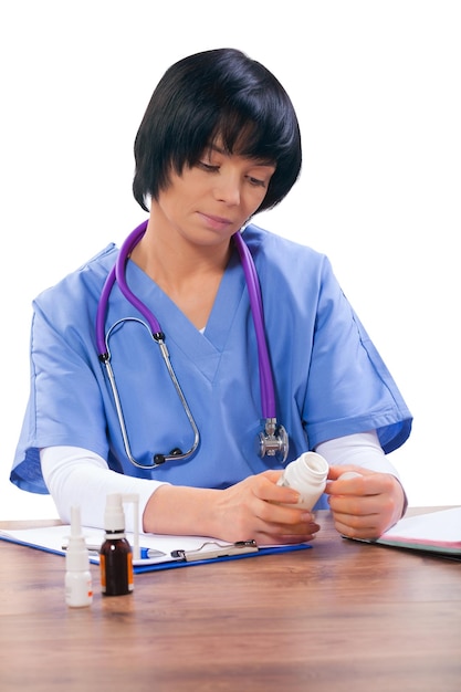 Asian female doctor sitting at table and holding bottle of pils