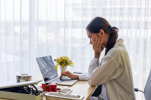 Asian female doctor watched A headache job in a notebook