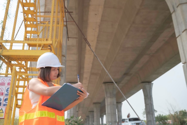 An Asian female engineer works at a motorway bridge construction siteCivil worker inspecting work on crossing construction