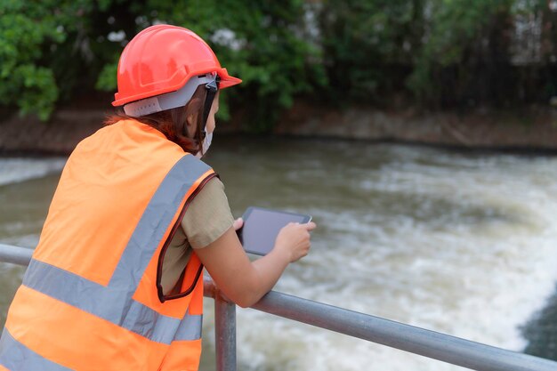 Asian Female engineering working xA at sewage treatment plantMarine biologist analysing water test resultsWorld environment day conceptCheck the PH value of the water before using it for treatment