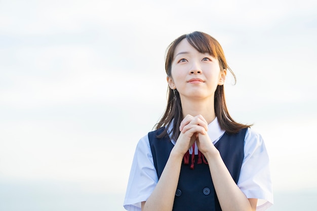 Asian female high school student in prayer pose outdoors